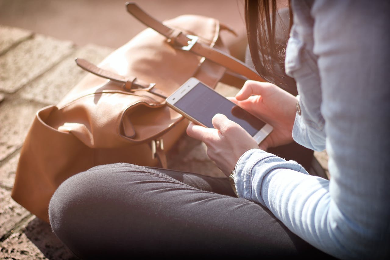 junge Frau blickt auf Smartphone Warum tritt Kurzsichtigkeit bei Jugendlichen immer öfter auf