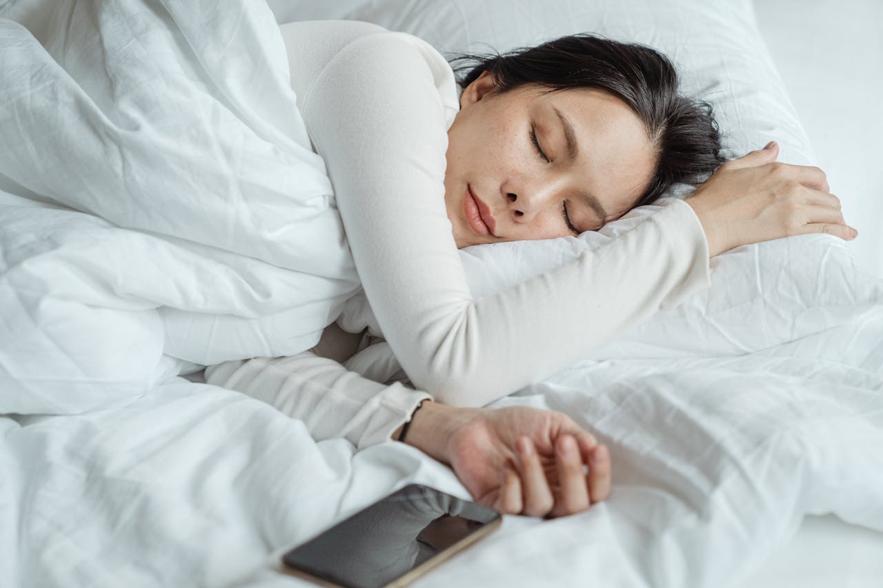 Frau Bett schlafen Smartphone Wenn Gedanken nicht stoppen – Einschlafprobleme durch Overthinking
