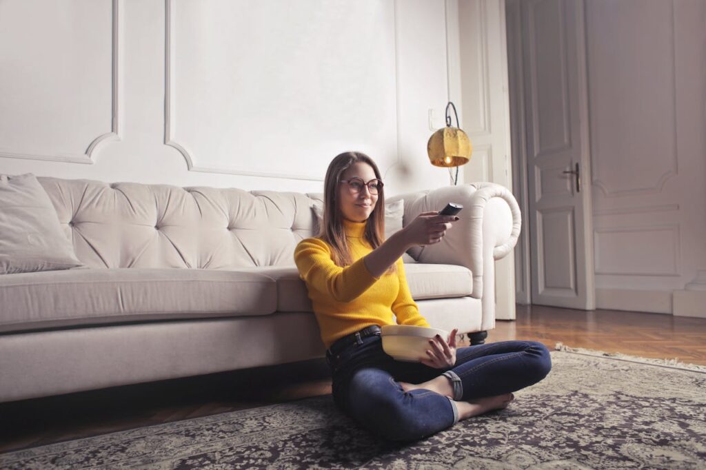 Frau Fernbedienung Fernsehen Popcorn Mädelsabend mit Horrorfilmen planen – so wird’s unvergesslich