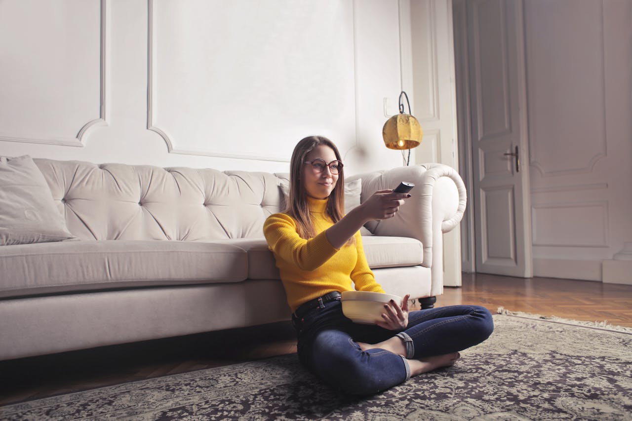 Frau Fernbedienung Fernsehen Popcorn Mädelsabend mit Horrorfilmen planen – so wird’s unvergesslich