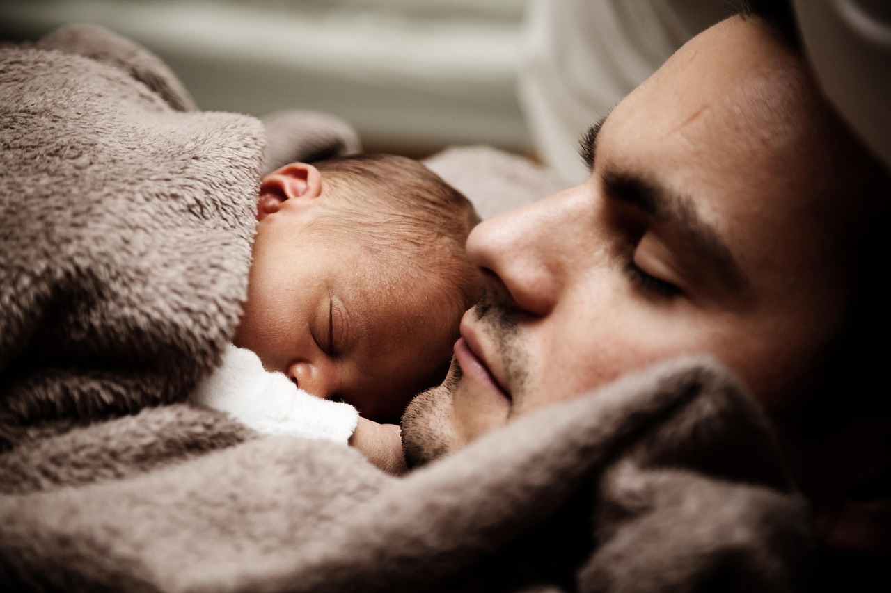 Vater und Baby schlafen Den werdenden Papa überraschen Kreative Ideen, um das Babygeschlecht zu verkünden